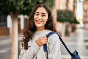 Smiling young girl with braces wearing a backpack outdoors
